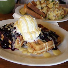 Waffles with whipped cream and other breakfast items on the table