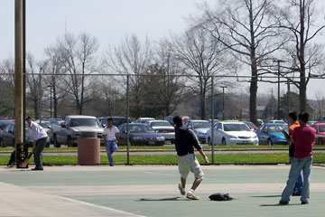 Guys playing cricket on tennis court