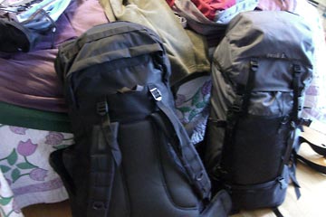 Two big backpacks propped up against the bed