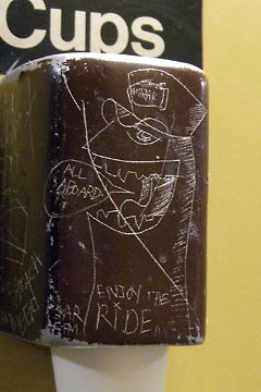 Drawing of train conductor scratched on paper cup dispenser