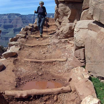 Joanne walking down switchback with blue sky in background