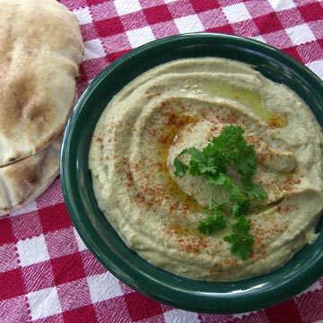 Plate of baba ganoosh garnished with parsley, set on checked tablecloth