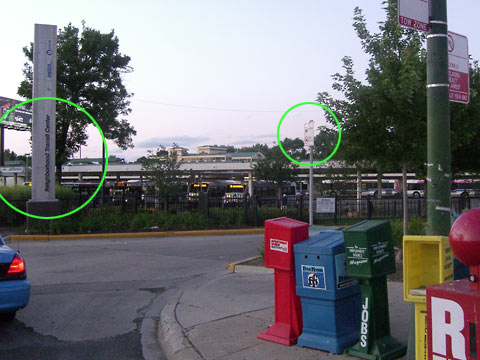 Picture of driveway into transit center showing large vertical sign on left and small sign on right