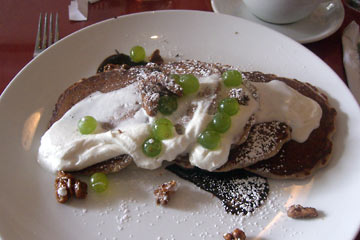 Plate of pancakes with whipped cream, grapes and pecans