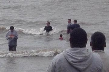 People standing in Lake Erie waves on a windy day