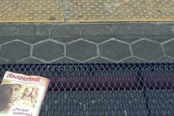 Train platform with yellow warning stripe, religious booklet on bench