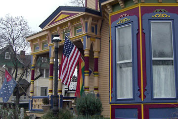 Front of multi-colored Victorian house with three different flags