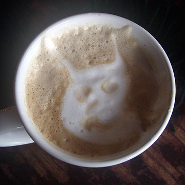 Cup of latte with bunny-type creature in the foam