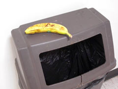 Single banana on top of trash container