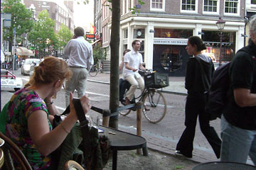 View of street from cafe table, with people walking and riding bikes.