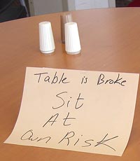 Sign on table saying "Sit at own risk"
