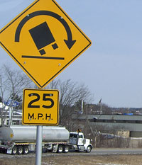 Highway warning sign showing truck tipping over