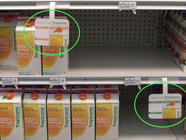 Tropicana orange juice on store shelves with small signs pointing to different varieties