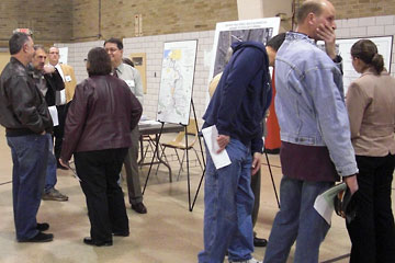 People standing around talking, maps in background