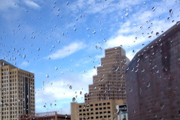Blue sky and clouds outside rain-spattered window