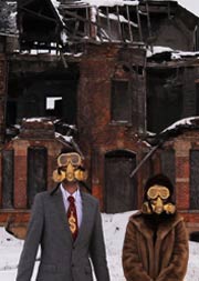 People in gas masks in front of burned out building
