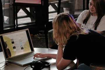 Two young women playing with work on laptops