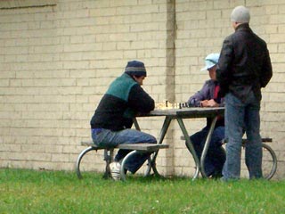 Two chess sitting at a picnic table against the building
