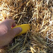 Using utility knife to chop hole in straw bale