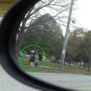 Woman carrying package on her head, seen in my rearview mirror