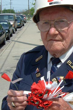 Elderly veteran in uniform selling red paper poppies