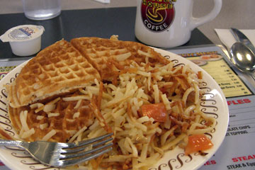 Plate of waffles and hash brown potatoes, cup of coffee
