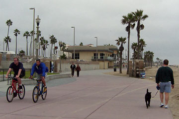 Man with dog, bikers and walkers on Huntington Beach boardwalk