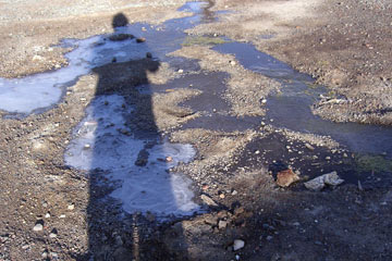Shadow of man on puddles of ice