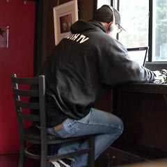 Man in "Truth TV" hoodie recording video on computer