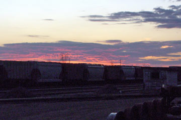 Magenta and purple clouds at sunset over trainyard