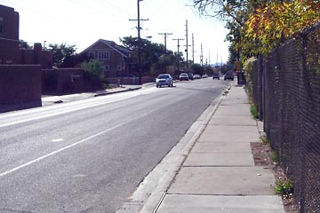 Looking down a street with lots of concrete and fences