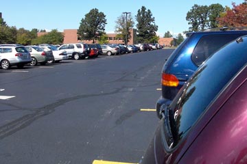 Cars in parking lot, looking down long aisle to building