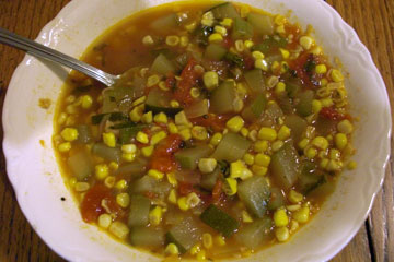Bowl of vegetable soup with lots of corn and zuccini
