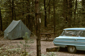 Green canvas tent and station wagon in woods