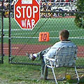 Guy watching football game next to "stop war" sign